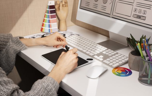 Un designer grafico al lavoro in uno studio creativo, utilizzando una tavoletta grafica e strumenti di design per la progettazione digitale.