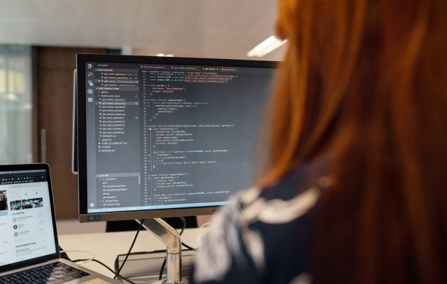Professionista che sviluppa codice su schermo, rappresentazione della digitalizzazione e automazione dei processi fiscali europei.